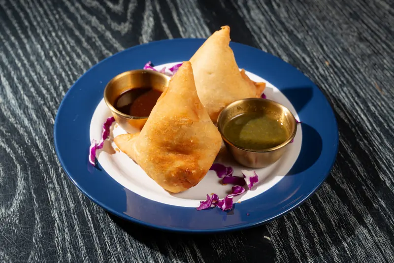 Two samosas with dipping sauces